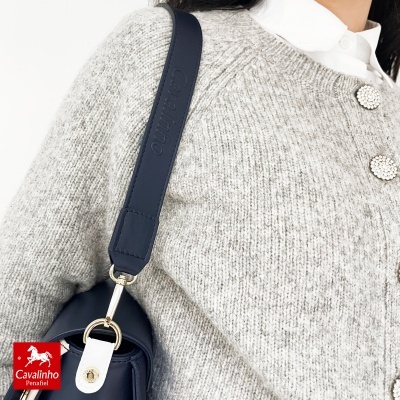 Mala castanho escuro com alça azul e camisola cinza com botões brilhantes