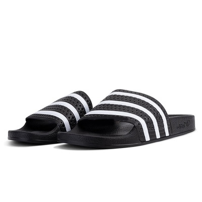 Chinelos slide pretos com três riscas brancas sobre fundo branco.