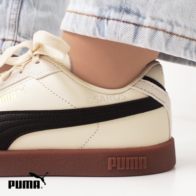 Ténis Puma bege com listra preta e sola castanha usado com calças de ganga