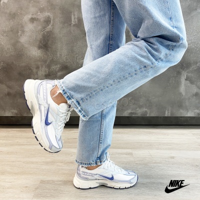 Ténis Nike brancos e azuis usados com calças de ganga claras