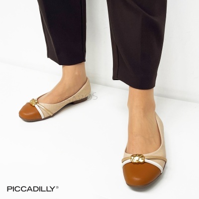 Sapatilhas bicolores bege e castanho com detalhe dourado, usadas por modelo em fundo branco