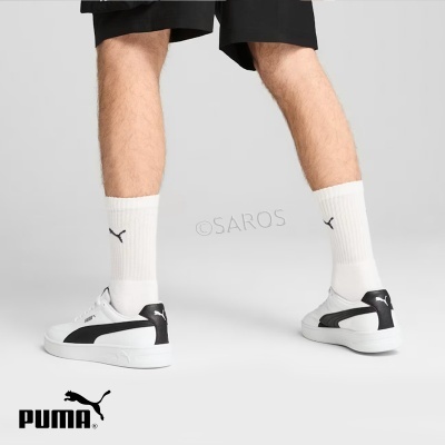 Ténis brancos e pretos da PUMA com meias brancas e fundo cinza