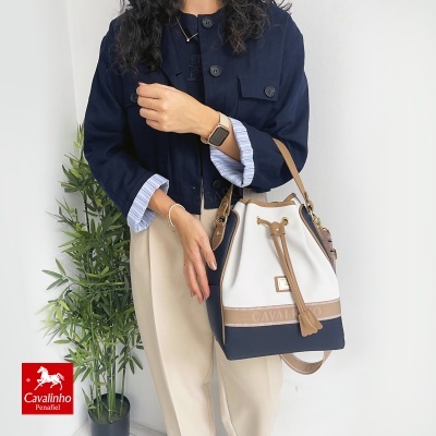Bolsa Cavalinho Peneia saco branco bege azul marinho com fecho em cordão, mulher com casaco azul e planta verde