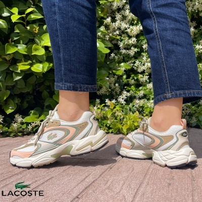 Ténis Lacoste creme com detalhes coloridos usados com jeans azul ao ar livre