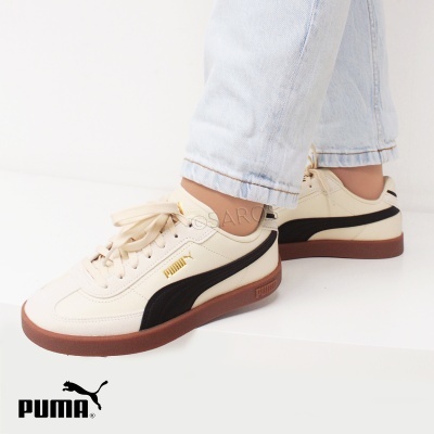 Ténis Puma creme com risca preta e sola castanha usados com jeans claros em fundo branco