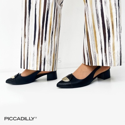 Sapatos pretos de salto baixo com detalhe dourado e calças riscas verticais brancas e castanhas