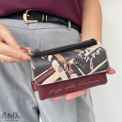 Carteira AneKke castanha e preta com padrão abstrato e letras metálicas.