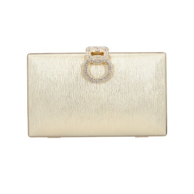 Carteira de mão dourada com fecho decorativo de cristais sobre fundo branco