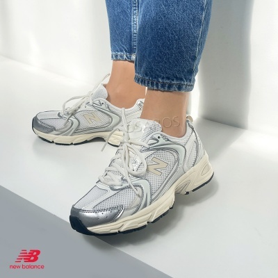 Tênis New Balance cinza e branco com calças de ganga azuis