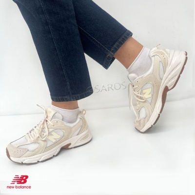Ténis New Balance creme e bege usados com meias brancas e calças de ganga