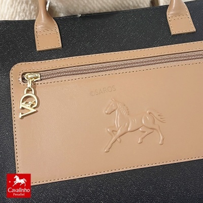 Bolsa preta com bolso bege em pele com cavalo em relevo e fecho com pendente dourado