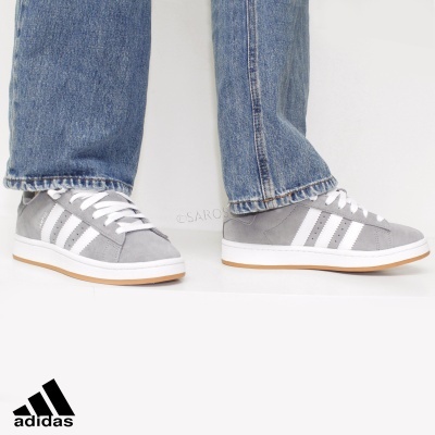 Ténis Adidas cinzentos com listas brancas e sola bege usados com calças de ganga azul claro