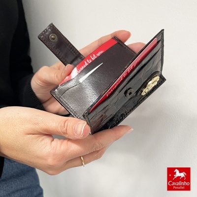 Carteira preta em pele com textura tipo crocodilo aberta a mostrar cartões vermelhos