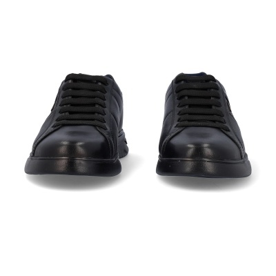 Sapatilhas pretas em pele com atacadores pretos e sola preta sobre fundo branco