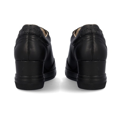 Sapatos pretos de pele vistos de trás com salto blocado e texto gravado no calcanhar