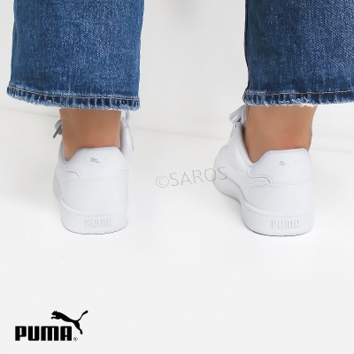 Ténis brancos Puma em piso branco com calças de ganga azuis
