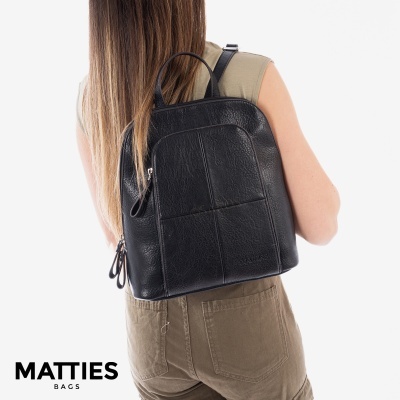 Mochila preta em couro sintético com zíper e textura, usada nas costas de uma pessoa.