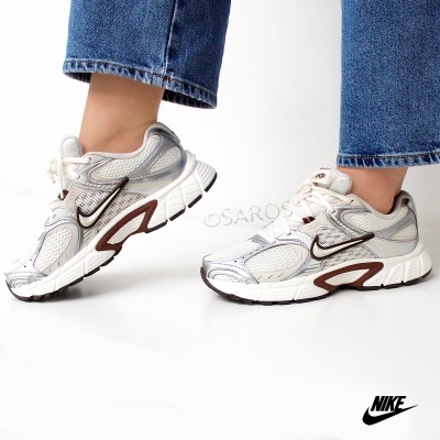 Sapatilhas desportivas Nike cinzentas com detalhes castanhos e brancos, usadas com jeans azuis.