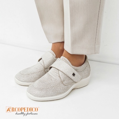 Sapatos brancos Arcopedico com padrão e fecho em tira, usados com calças bege