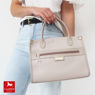 Bolsa bege claro com pegas e fecho frontal, usada por pessoa de camisa branca e jeans claros