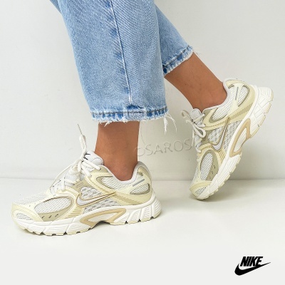 Ténis Nike brancos e bege com sola espessa usados com jeans azuis claros