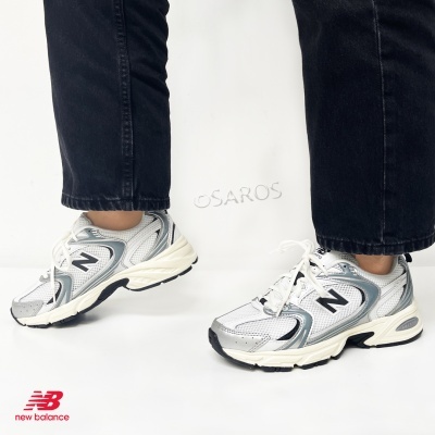Ténis New Balance brancos e cinza com detalhes pretos usados com calças pretas
