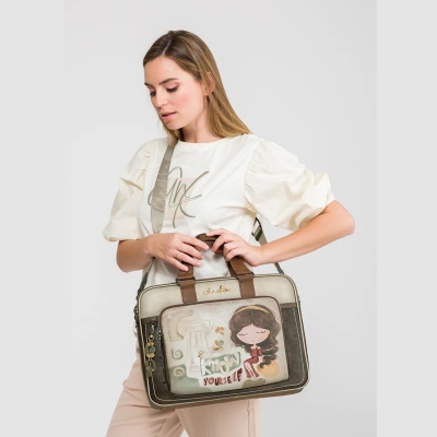 Mala em tons dourado e castanho com ilustração e texto KNOW YOURSELF, segurada por mulher com blusa creme e calças claras
