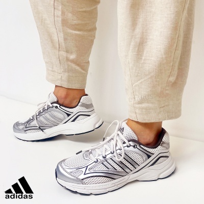 Sapatos desportivos Adidas brancos e prata em modelo com calças beges