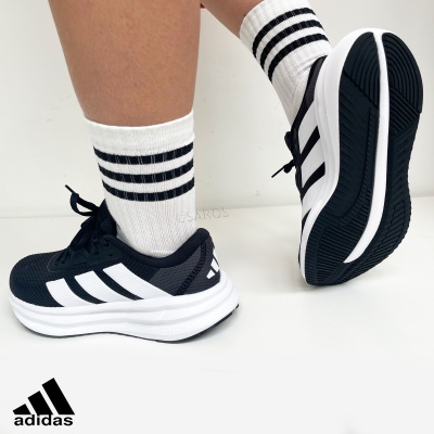 Ténis adidas pretos com riscas brancas e meias brancas com riscas pretas.