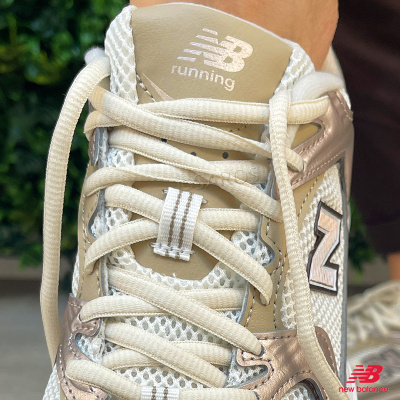 Ténis de corrida New Balance bege e branco com atacadores brancos e detalhes metálicos