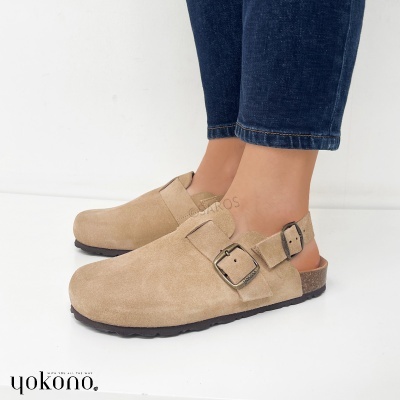 Sapatos tipo mule camurça bege com fivela metálica e sola preta, usados com calças de ganga