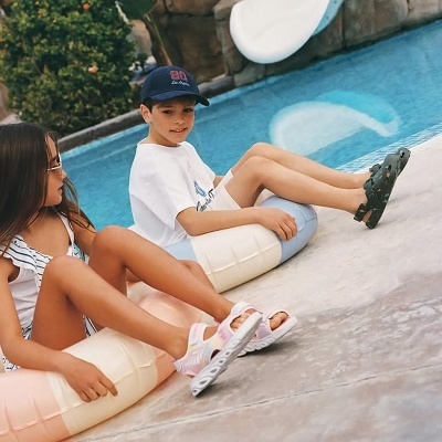 Duas crianças sentadas em almofadas infláveis à beira de piscina.