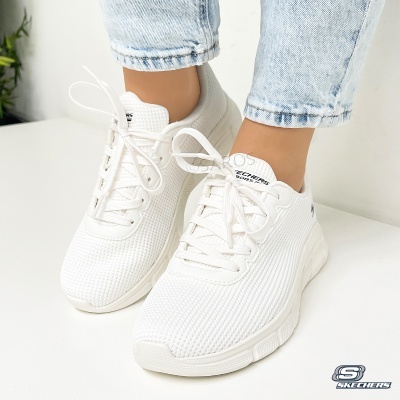 Ténis Skechers brancos em malha respirável usados com calças de ganga claras