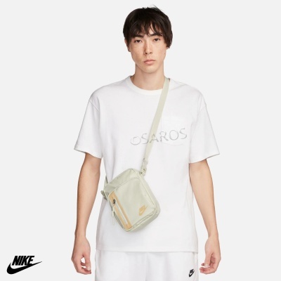 Homem com t-shirt branca e mochila pequena bege com logótipo da Nike
