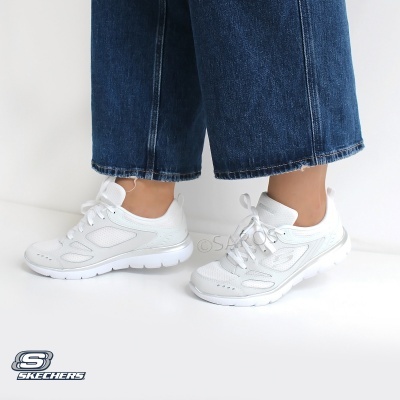 Ténis brancos Skechers com sola grossa usados por pessoa com calças de ganga azuis.