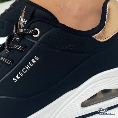 Ténis pretos Skechers com detalhes dourados e sola branca