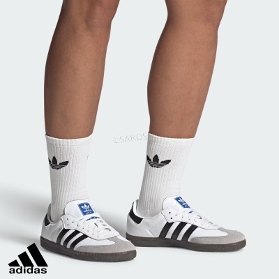 Ténis Adidas brancos com riscas pretas e meias brancas com símbolo Adidas