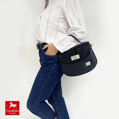 Bolsa preta de couro com textura tipo crocodilo usada ao ombro