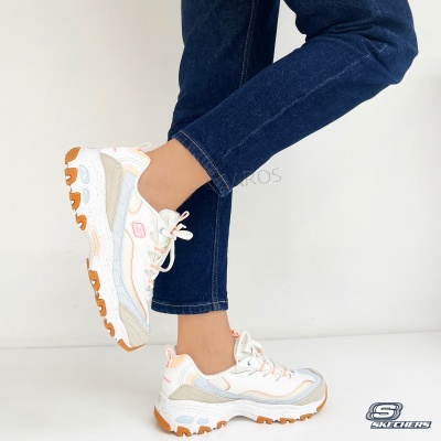Ténis Skechers branco com detalhes laranja e cinza usados com calça jeans
