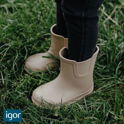 Botas de criança bege claro em relva verde com calças pretas