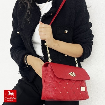 Mala vermelha matelassê com alça de corrente dourada e correia vermelha usada à tiracolo.