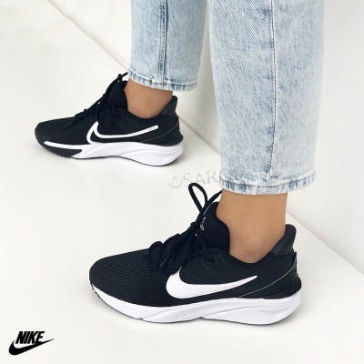 Ténis desportivos Nike pretos com sola branca usados com jeans