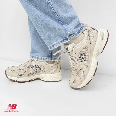 Ténis New Balance bege com detalhes em malha e couro usados com jeans azuis