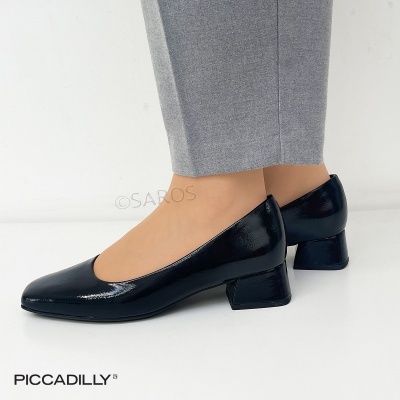 Sapatos pretos de verniz com salto médio usados com calças cinzentas.