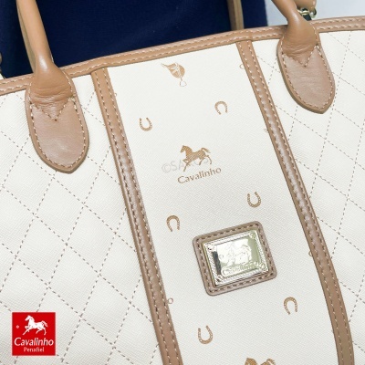 Mala bege e castanha com padrão de cavalos e ferraduras e etiqueta metálica Cavalinho