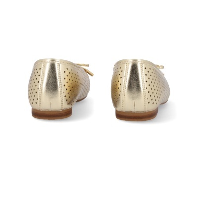 Sapatos sapatilha dourados com padrão de furos vistos de trás numa superfície branca