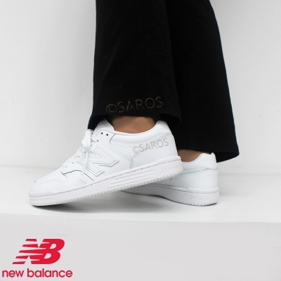 Ténis brancos New Balance com logótipo SAROS, usados com calças pretas