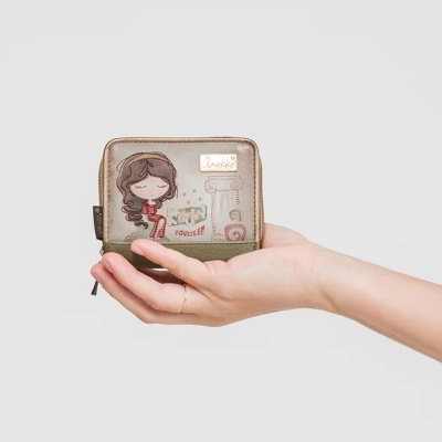 Carteira pequena verde bege com desenho de menina e texto segurada por mão.