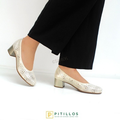 Sapatos creme de senhora com salto médio e pele perfurada em fundo branco