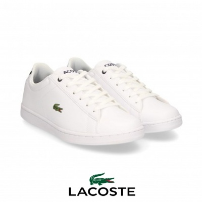 Par de sapatilhas brancas Lacoste com logo crocodilo verde e atacadores brancos sobre fundo branco